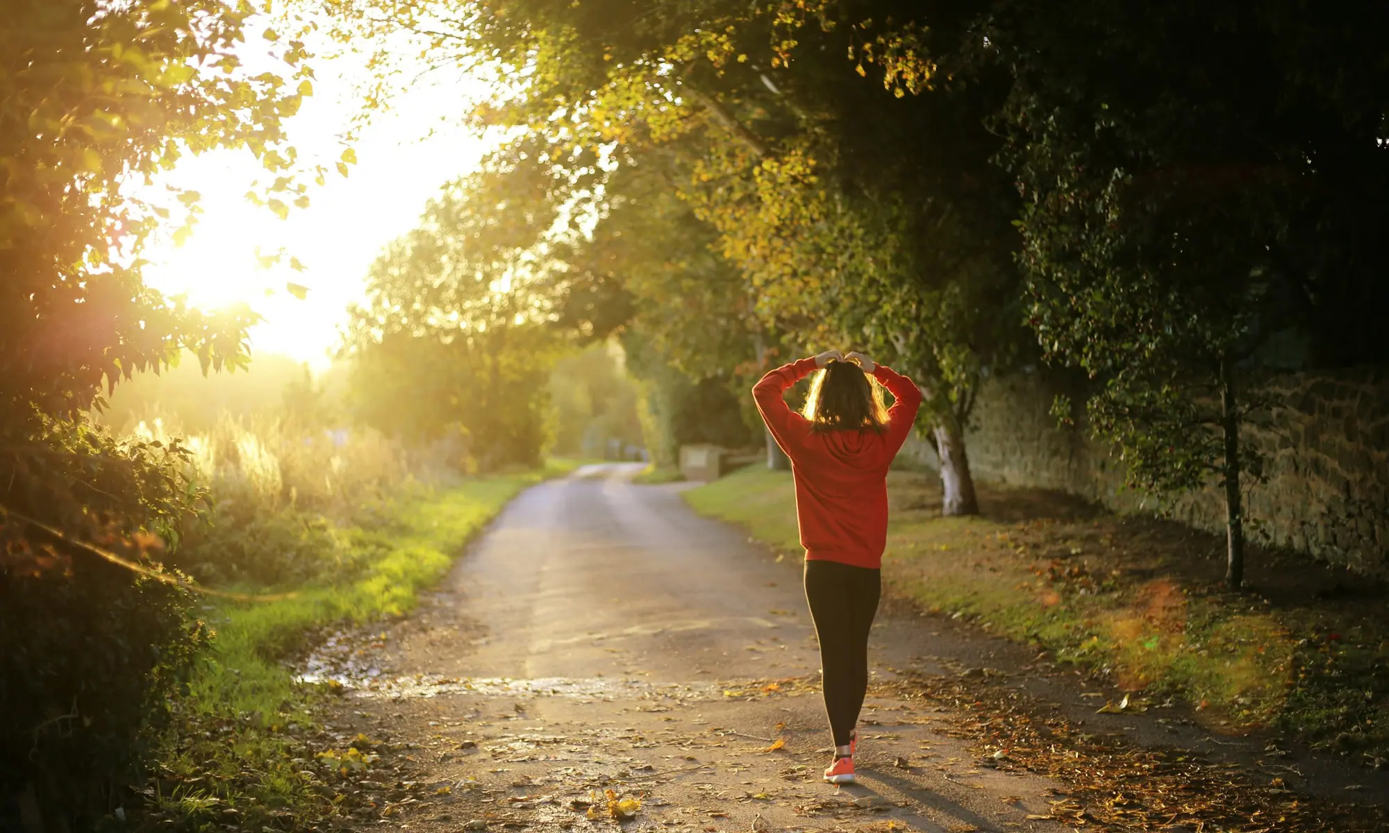 Woman walking a tree-lined path at sunrise — medical weight management in Modesto, CA